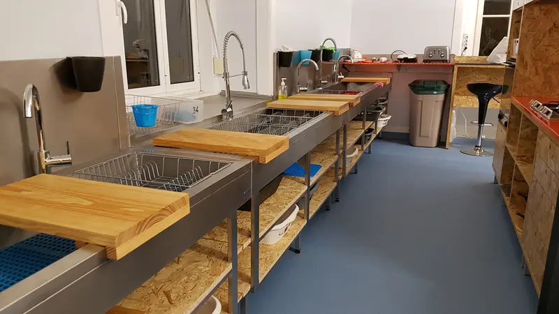 Cozinha comum com bancadas e lava-loiças em inox